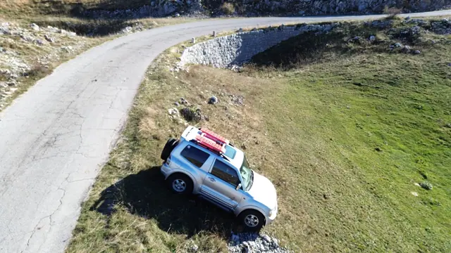 Pogled iz vazduha na terenac uz krivinu planinskog puta